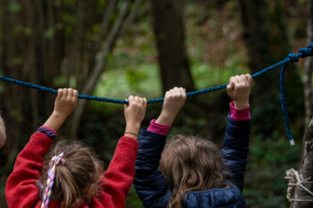 bambini giocano appesi ad una corda nel bosco