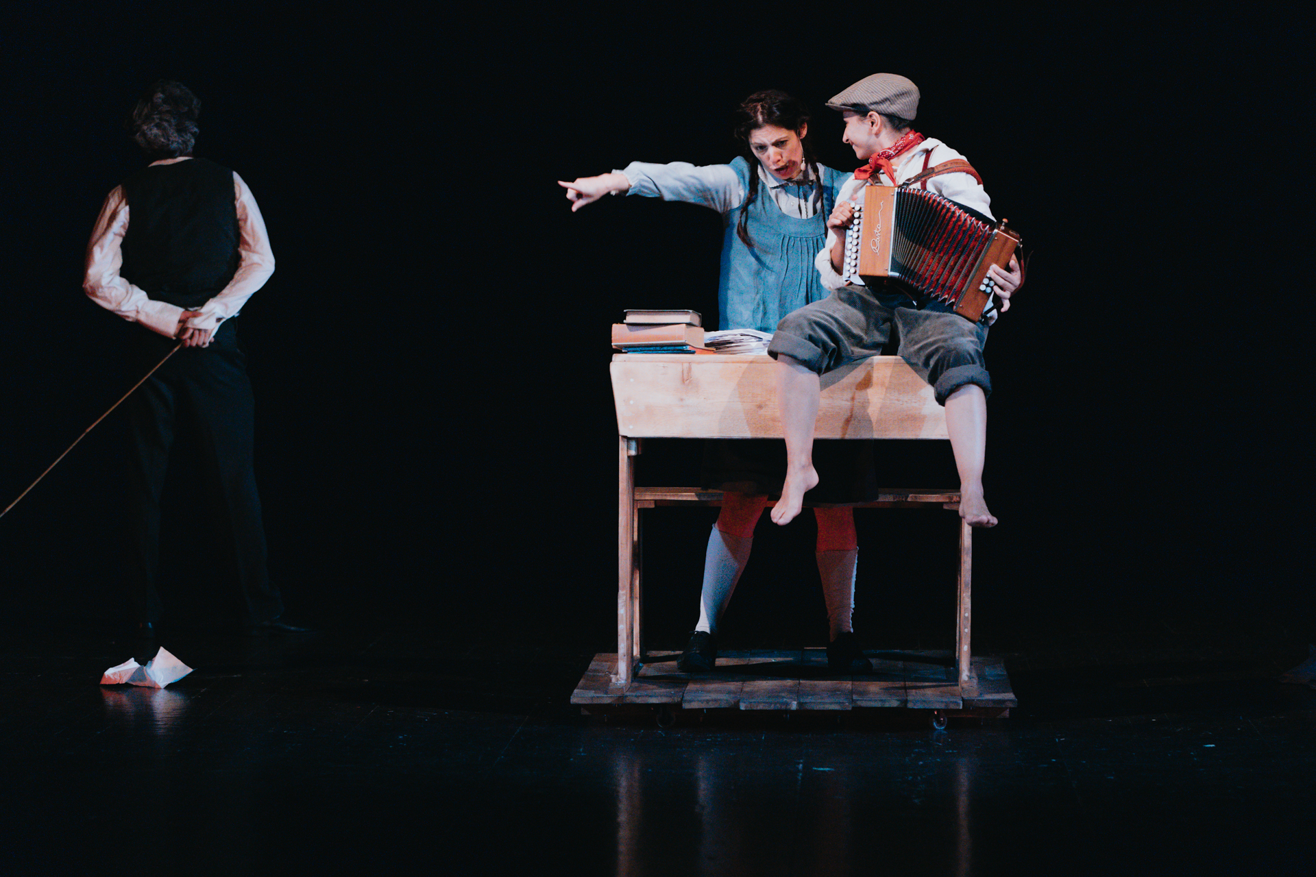 tre giovani attori in scena con un organetto